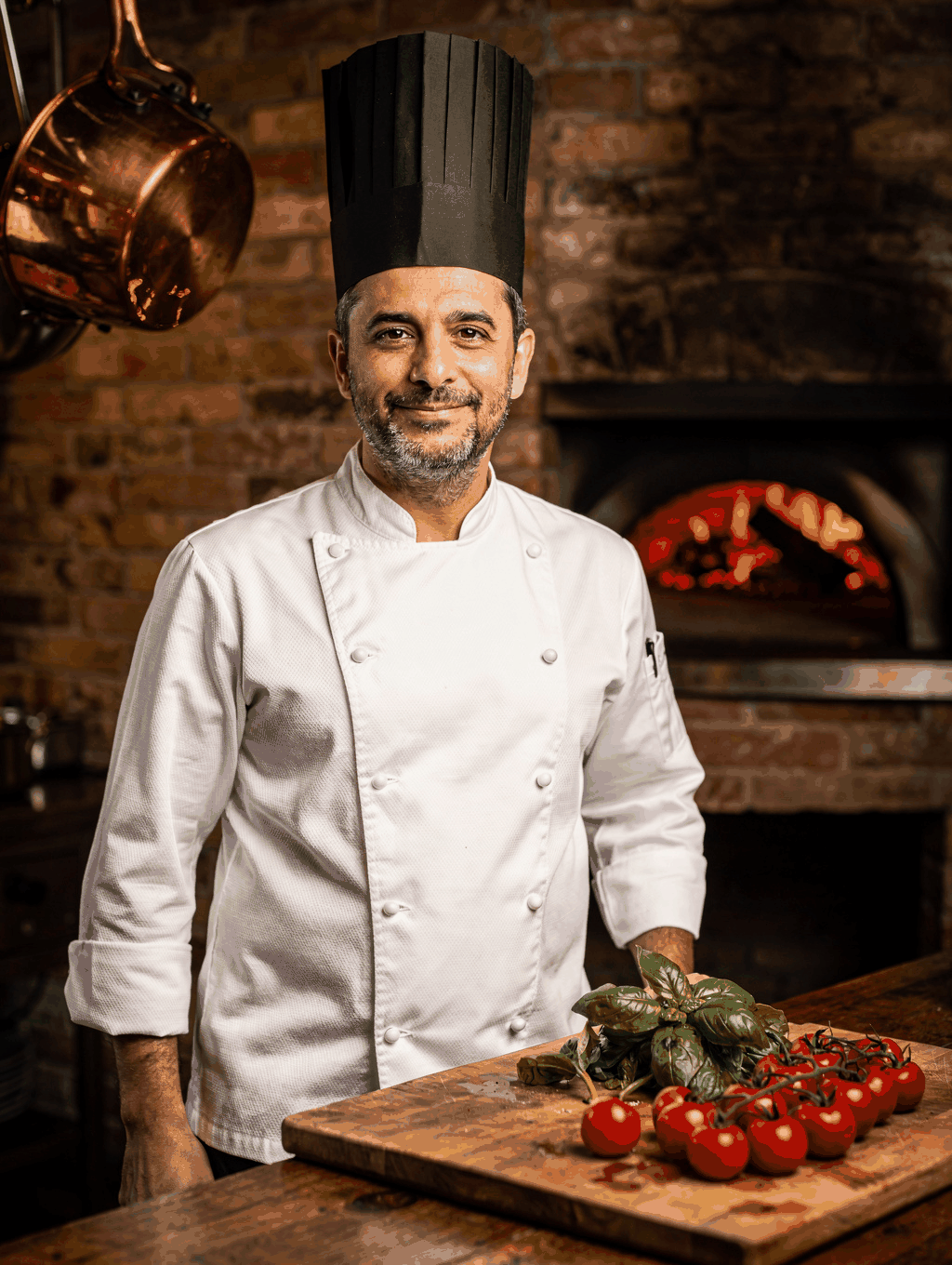 Chef Alessandro Conti preparing wood-fired dishes in the kitchen